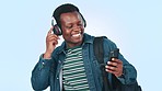 Music, headphones and black man in studio with phone for streaming song, radio and audio. Happy, student and person listening to track, dance and excited for university or college on blue background