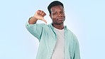 Hand, thumbs down and face of black man with review, feedback or disagreement vote on blue background in studio, Negative, opinion and gesture with hand to mockup space with mistake, fail or info