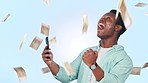 Phone, money rain and man for success, wow and winning lottery, online gambling or competition in studio. Cash in air, financial freedom and african person or winner yes on mobile and blue background