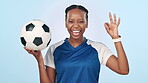 Face, soccer and ok sign with sports, black woman and fitness on blue studio background. Portrait, African person or football player with happiness, promotion or agreement with perfect, icon or smile