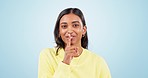 Secret, woman whisper and face in studio with fashion, gossip and confidential news with blue background. Smile, silence sign and female person with portrait, privacy and quiet voice for announcement