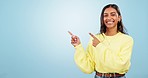 Smile, dance and face of woman with hand pointing in studio for deal, giveaway or promo on blue background. Excited, news and portrait of Indian female model show sale, discount or prize announcement