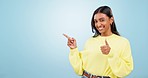 Pointing, thumbs up or face of happy woman by mockup space isolated on blue background in studio. Okay, review or Indian girl with like, agreement or yes sign for discount or promo announcement offer