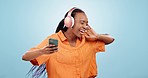 Dance, headphones and black woman with phone in studio to celebrate freedom, karaoke party and audio on blue background. Excited model listening to mobile music, radio and singing sound with energy