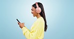 Phone, headphones or happy woman in studio on social media, mobile app or internet to scroll online. Chat network, music search or girl typing on digital technology web on blue background in profile