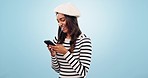 Phone, smile and woman in a studio typing message on social media, mobile app or the internet. Technology, happy and young Indian female model networking on website with cellphone by blue background.