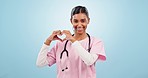 Heart, hands and face of woman doctor in studio with love, hope or empathy sign on blue background. Kindness, portrait and female nurse with support, emoji or thank you symbol for donation or charity