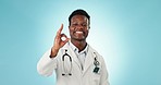 Doctor, okay sign and face of black man in studio for agreement, approval and yes for medicine. Healthcare, portrait and person with ok hand for medical service, care and wellness on blue background