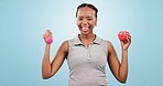 Face, dumbbells and black woman with exercise, apple and wellness on a blue studio background. Portrait, African person and model with workout, fitness and equipment with training, fruit and health