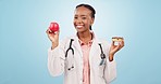Face, doctor and black woman with an apple, donut and healthcare on a blue studio background. Portrait, African person and medical professional with fruit, nutrition and decision with sweet treats