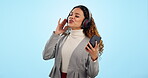 Phone, music and dance with a woman on a blue background in studio for freedom, energy or wellness. Radio, streaming and headphones with a happy young gen z person singing to audio sound to relax