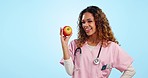 Doctor, woman and apple in studio, smile and face for diet, health and choice by blue background. Excited nutritionist, nurse or medic with fruit, review or feedback for healthcare choice in portrait