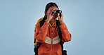 Binocular, backpacker or woman excited, travel or hiking with adventure on a blue studio background. Person, model or traveler with bird watcher, holiday or vacation with journey or hiker with health