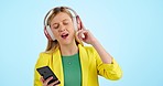 Woman, headphones and phone for singing to music, dance with happy energy and mental health on a blue background. Young person or student listening to mobile music and streaming service in studio