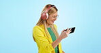 Woman, dancing and listening to music on headphones, mockup and studio by blue background. Happy person, movement on hearing audio, sound and song by streaming radio on phone for fun and glasses