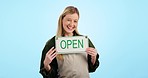 Happy woman, small business and open sign for welcome or advertising against a blue studio background. Portrait of female person or waitress with billboard, poster or calling in ready for service