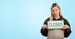 Closed sign, face and sad pointing to shop, retail and business bankruptcy in studio. Mockup space, female entrepreneur and cafe placard with poster to show closure announcement with blue background