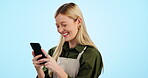 Waitress, happy woman and phone for social media, funny networking and coffee shop chat in studio. Young entrepreneur, business woner or cafe worker typing on mobile and laughing on a blue background