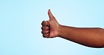 Hands, closeup and person with thumbs up in studio for support, feedback or review on blue background. Zoom, finger or model show emoji for success, yes or thank you, motivation or vote agreement 