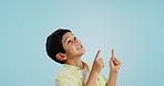 Kid, boy and smile while pointing in studio on blue background with mockup for announcement, offer or deal. Youth, happy and excited about notification on social media, online or digital marketing