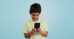 Kid, phone or typing to chat in studio on social media to play mobile games or download app. Blue background, scroll or boy child reading notification for online communication or watch fun multimedia