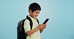 School, phone or kid on social media in studio typing to chat, play mobile games or download app. Blue background, student or happy boy child reading notification for online education or tech search