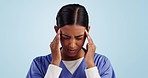 Headache, nurse and woman with stress, burnout and anxiety from career at hospital or clinic in studio. Pain, medical and healthcare professional with breathing for migraine with blue background