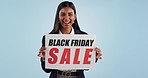 Sale sign, black friday and woman face excited from shopping deal, promotion and poster in studio. Happy, portrait and smile with announcement promo on paper for advertising with blue background