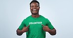 Volunteer, black man smile and laughing face with pointing to NGO, logo and charity tshirt in studio. Nonprofit, portrait and African male person happy from activist platform with blue background