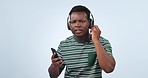 Dance, music and black man listening on a studio background for radio, podcast or audio. Happy, contact and an African person wit headphones and mobile for streaming app with a stop for conversation