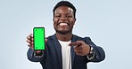 Happy black man, phone and pointing to green screen in advertising against a studio background. Portrait of African businessman showing mobile smartphone app, display or mockup with tracking markers