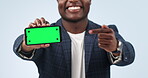 Happy man, phone and pointing to green screen in marketing or advertising against a studio background. Closeup of businessman showing mobile smartphone app, display or mockup with tracking markers