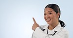 Studio face, happy woman and doctor point at healthcare direction, hospital service or clinic announcement, offer or ads. Nurse choice, mockup space and Japanese surgeon portrait on blue background