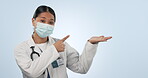 Woman, face mask and doctor point at palm product placement, wellness brand choice or cardiology service offer. Studio surgeon portrait, health mockup space and medical ambassador on blue background