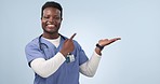 Black man, happy and doctor point at palm product placement, studio branding or cardiology service offer. Professional surgeon portrait, mockup space and African medical ambassador on blue background