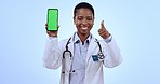 Cellphone, green screen and woman doctor with thumbs up in studio for approval, happy or agreement gesture. Tracking markers, mockup and African female healthcare worker with phone by blue background