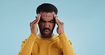 Stress, tired and a man with headache pain on a blue background from burnout or anxiety. Mental health, fatigue and a person with a migraine massage, frustrated and with depression and anger