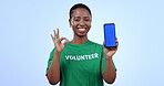 Woman, volunteer and mobile green screen, presentation mockup and okay hands, join us or marketing in studio. Face of African person on phone app or pointing to information for NGO on blue background