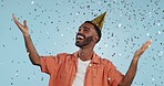 Man, birthday party hat and confetti in studio, smile or surprise for celebration by blue background. Person, event and excited with silver glitter, achievement or happy for winning with wow for goal