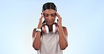 Fitness, studio and woman with headache at workout, training and massage with headphones. Stress, burnout and girl athlete with hands on head, injury or fatigue at gym exercise on blue background.