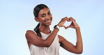 Heart, love and fitness portrait of woman with sign, hand gesture and isolated in a studio blue background for care. Support, health and person smile for wellness after exercise and calm symbol