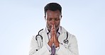 Praying, stress and black man doctor with anxiety, burnout and worry from surgery in studio. Healthcare, medical and wellness worker with empathy and religion hand sign with grief and blue background