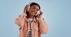 Happy woman, headphones and dancing to music, audio or sound track against a blue studio background. Female person smile and enjoying podcast or streaming in happiness with headset on mockup space