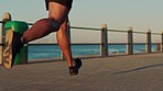 Fitness, beach and man running on promenade for outdoor run workout for endurance, health and speed. Sports, seaside and closeup of runner legs doing cardio exercise training for a race or marathon.