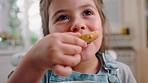 Face, girl and eating cookie in kitchen, happy and enjoy break. Young female, child and delicious biscuit for lunch, chewing tasty treat and snack for fun, portrait and happiness at home on vacation.