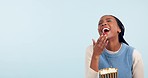 Black woman in studio, eating popcorn and watching tv with smile, mockup and comedy movie. Laughing, comic and happy girl on blue background with snacks for cinema film, tv or video streaming service