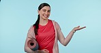 Fitness, hand and a woman in studio for happy advertising, announcement or mockup. Excited young female person on a blue background for choice, empty palm space and exercise or yoga mat offer