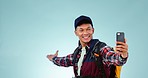 Backpack, travel and video call by man in studio for hiking, freedom or adventure on blue background. Camping, journey and male backpacker influencer with smartphone, app for live streaming blog post