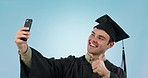 Graduation, man and studio selfie with smile, thumbs up and  achievement of learning goal by blue background. College student guy, photography and emoji for education, social media or profile picture