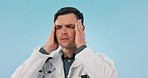 Burnout, man and doctor with stress, headache and healthcare on a blue studio background. Person, model and medical professional with a migraine, fatigue and pain with anxiety, overworked and tired